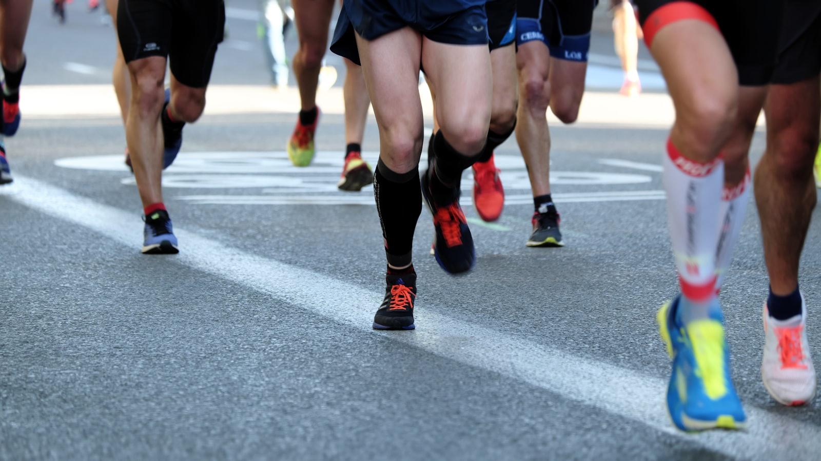 Atletas de corrida de rua em movimento, com foco nas pernas e tênis coloridos.