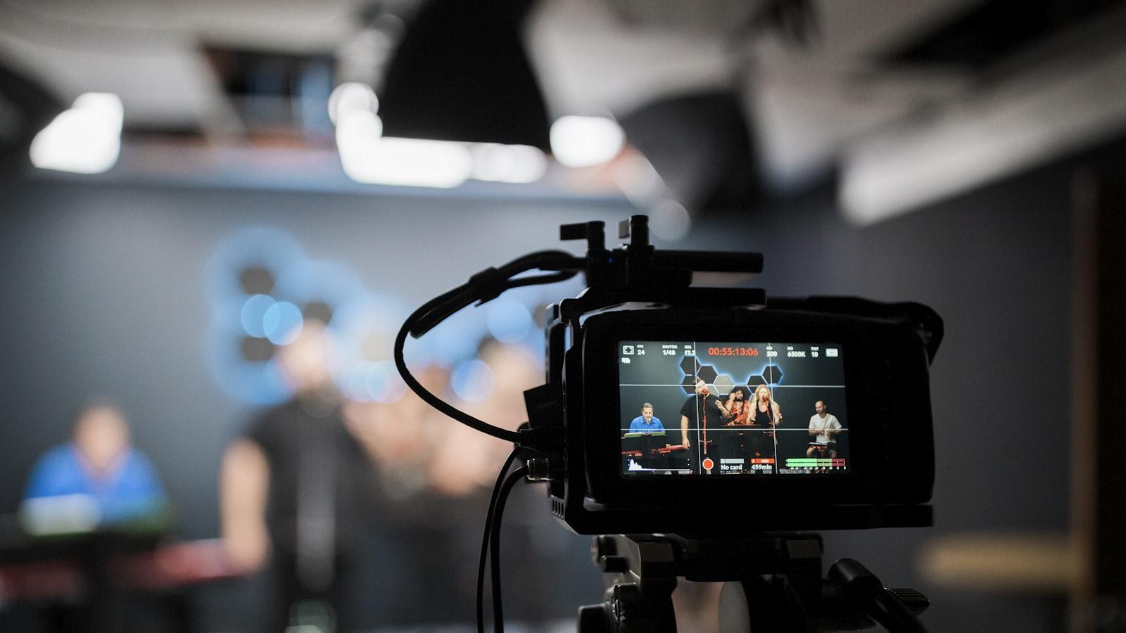 Câmera de cinema com monitor mostrando o take, e equipe ao fundo em um set publicitário.